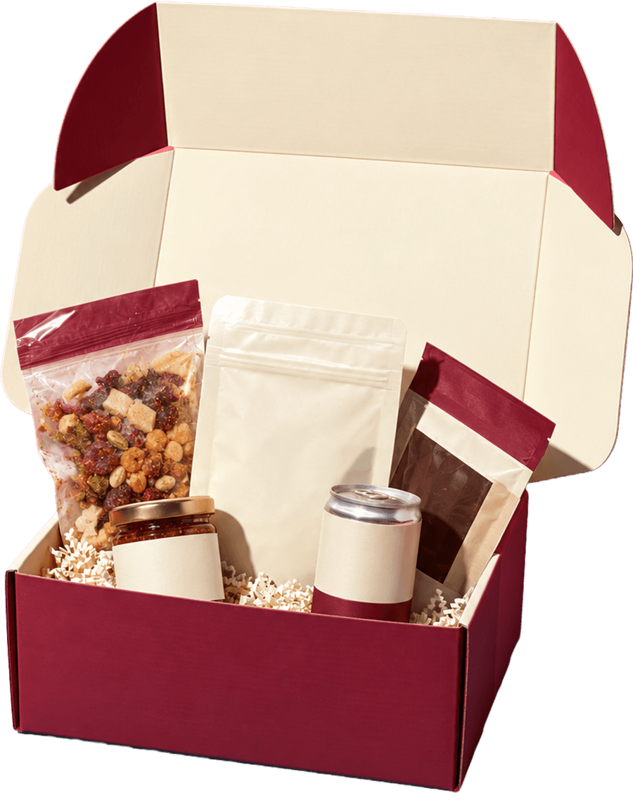 An open burgundy and cream gift box filled with snacks, a jar, and a can